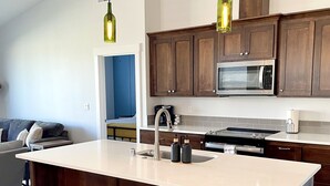 Una cocina moderna con una isla grande, taburetes de madera y armarios de madera oscura.