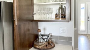 Una cocina con un armario de madera que contiene copas de vino y una botella.