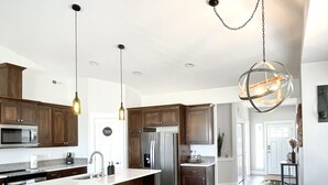 Una cocina moderna con una isla central, taburetes de bar y una mesa de comedor con sillas.