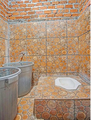 A bathroom with a unique tile design featuring circular patterns, a bathtub, and two large metal containers.