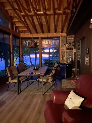 Enjoy a serene lake view from the comfort of this inviting space, featuring a dining area, bar, and cozy seating.