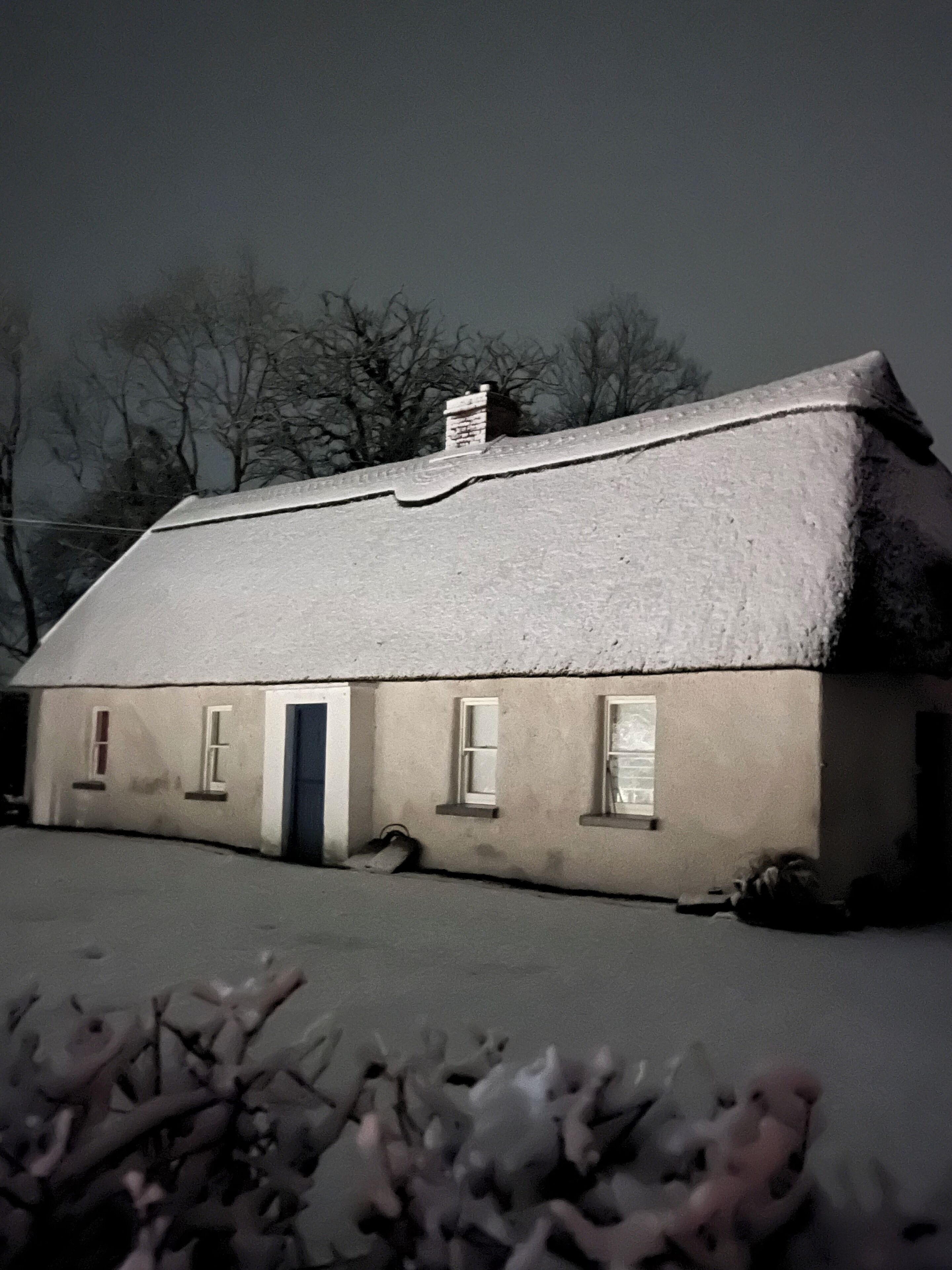 A snow-covered house with a chimney, windows, and a door.