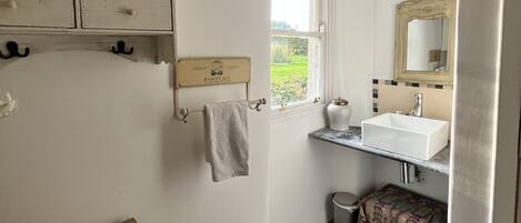 A bathroom with a wooden cabinet, a towel rack, a sink with a mirror, and a window.