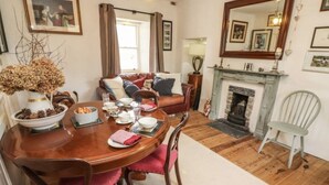 A dining room with a wooden table set for a meal, a sofa, a fireplace, and a mirror on the wall. - Irish Thatched cottage. Escape to a piece of living history on a country farm (Knocklong)