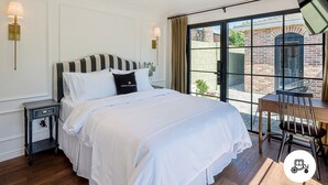 Un dormitorio con una cama grande, un escritorio con silla, un ventilador de techo y vistas al exterior.