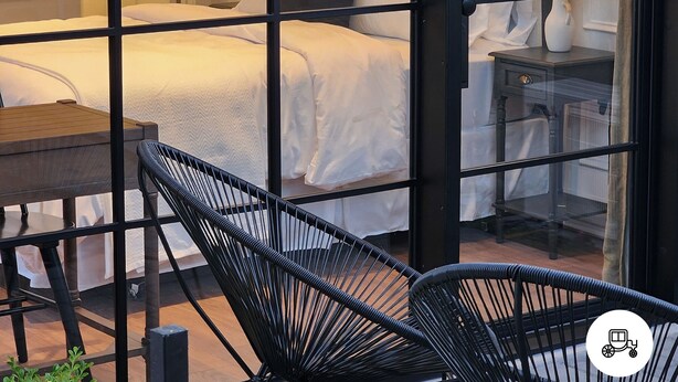 Una habitación de hotel moderna con una cama, una mesita, una silla y una mesita de noche.