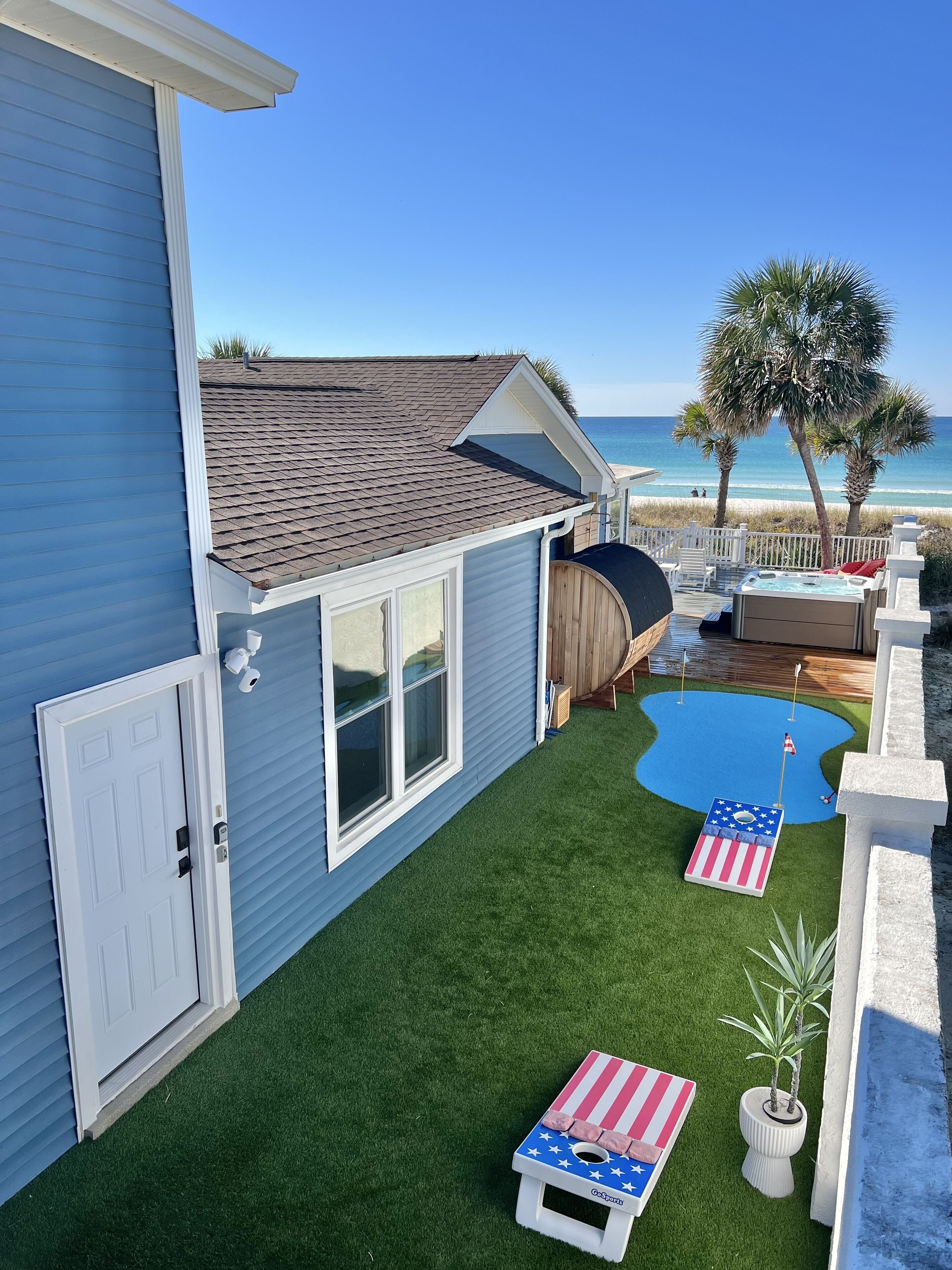 A backyard with artificial grass, a hot tub, and a small pool.
