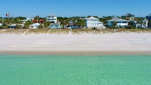 En ejendom ved stranden med en sandstrand og klart turkis vand.