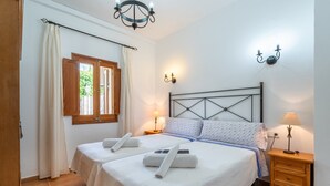 Une chambre double avec deux lits, un lustre, des lampes de chevet, une fenêtre avec des rideaux et une table de chevet en bois.