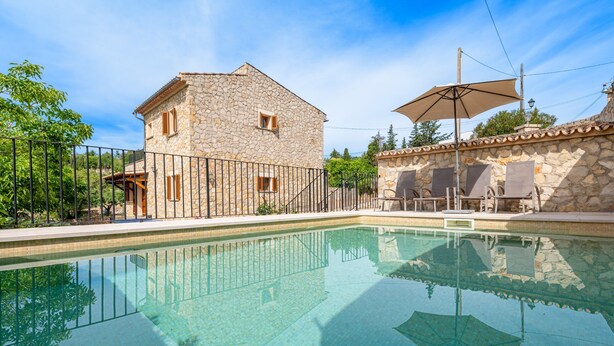 Un bâtiment en pierre doté d’une piscine, d’un espace extérieur aménagé et d’une pergola.