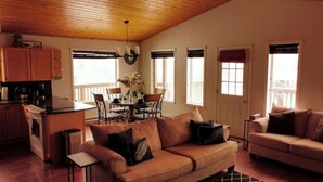 A cozy living room with a sofa, a dining table with chairs, and a kitchen area with wooden cabinets and a stove.