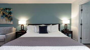 Une chambre d’hôtel avec un lit, deux tables de chevet avec des lampes, un canapé et un tableau au mur.