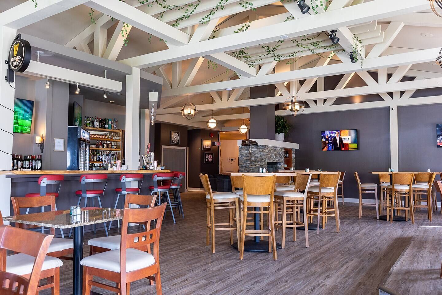 A restaurant with a bar area, wooden chairs, and a stone fireplace.