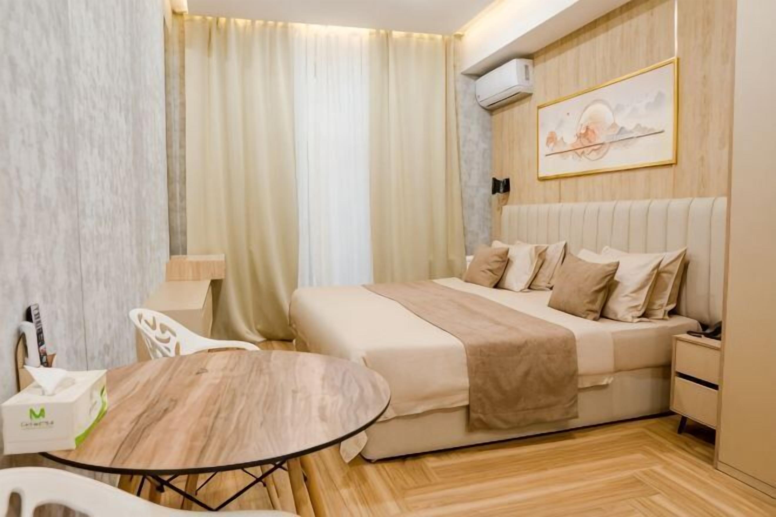 A hotel room with a bed, bedside table, and a round table.