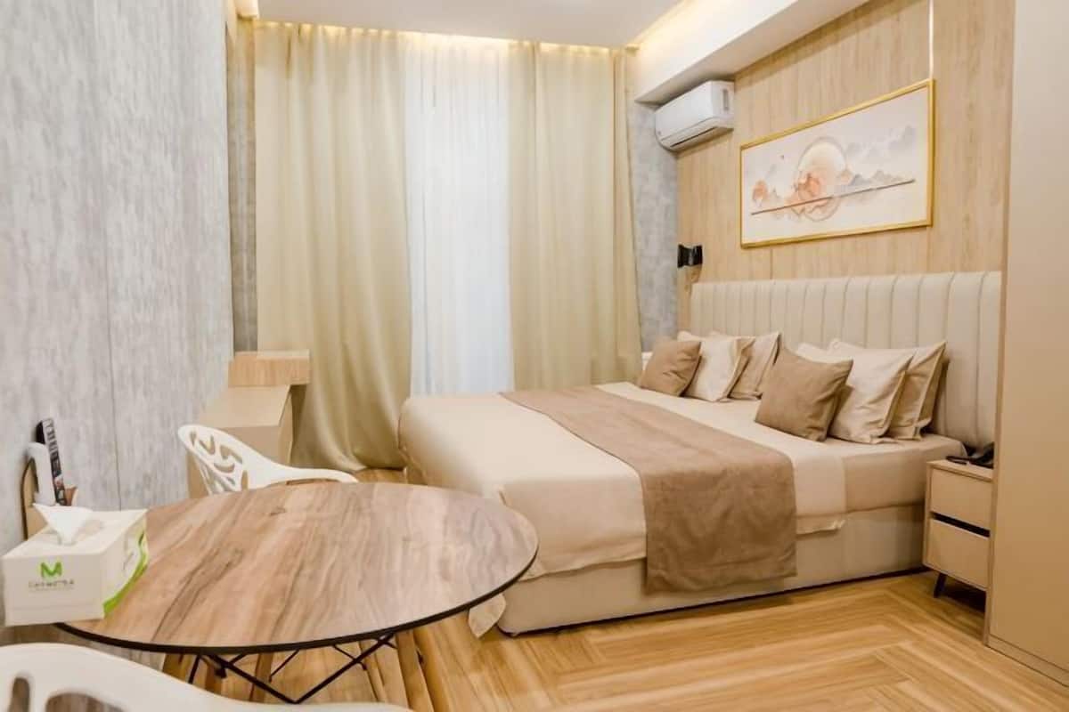 A hotel room with a bed, bedside table, and a round table.