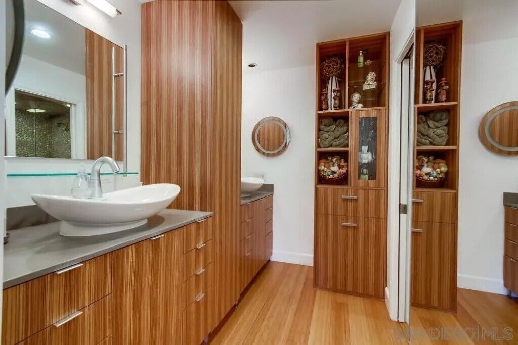Une salle de bain moderne avec des meubles en bois, un grand miroir et un lavabo intégré.