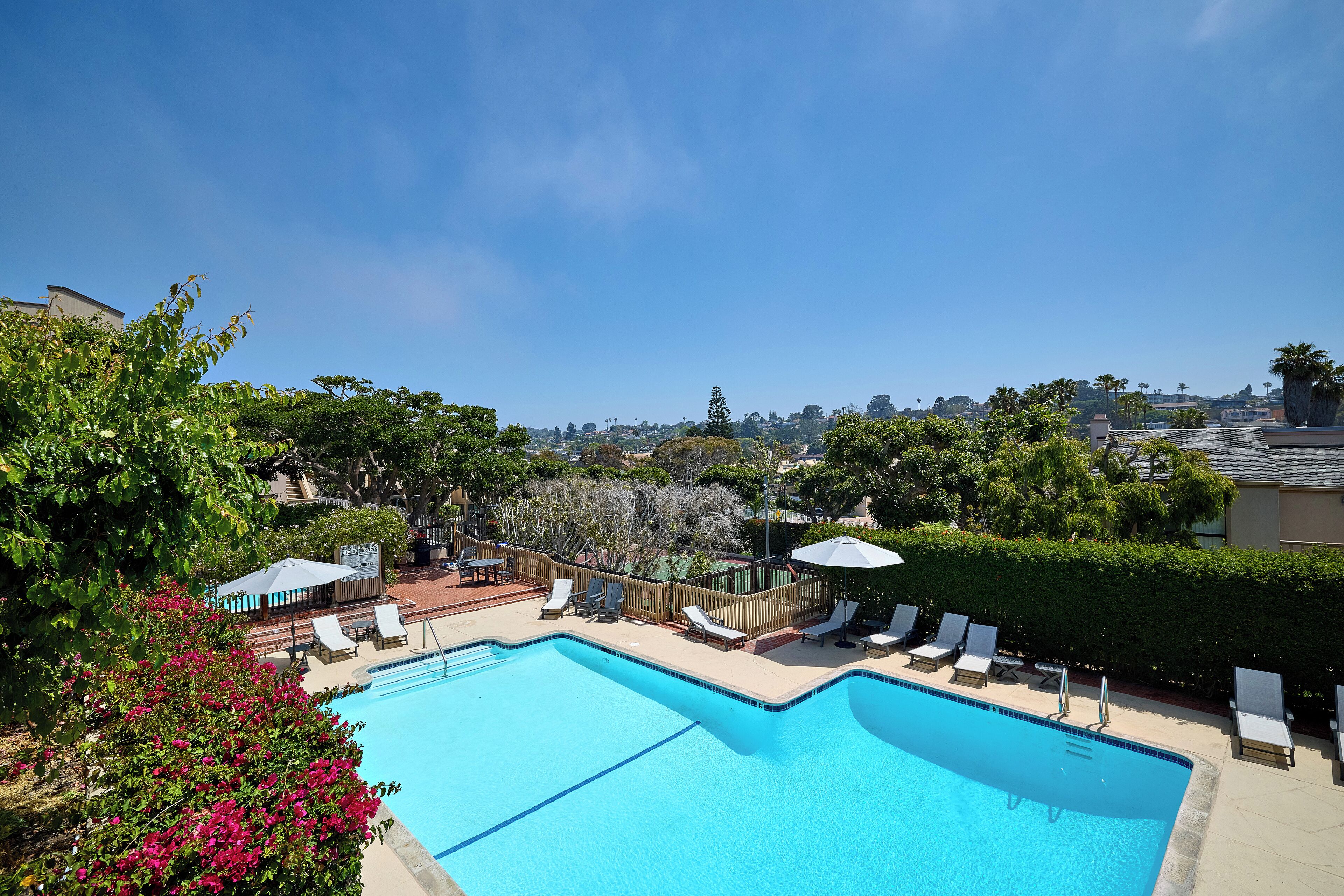 A swimming pool with lounge chairs and a view of the surrounding area.