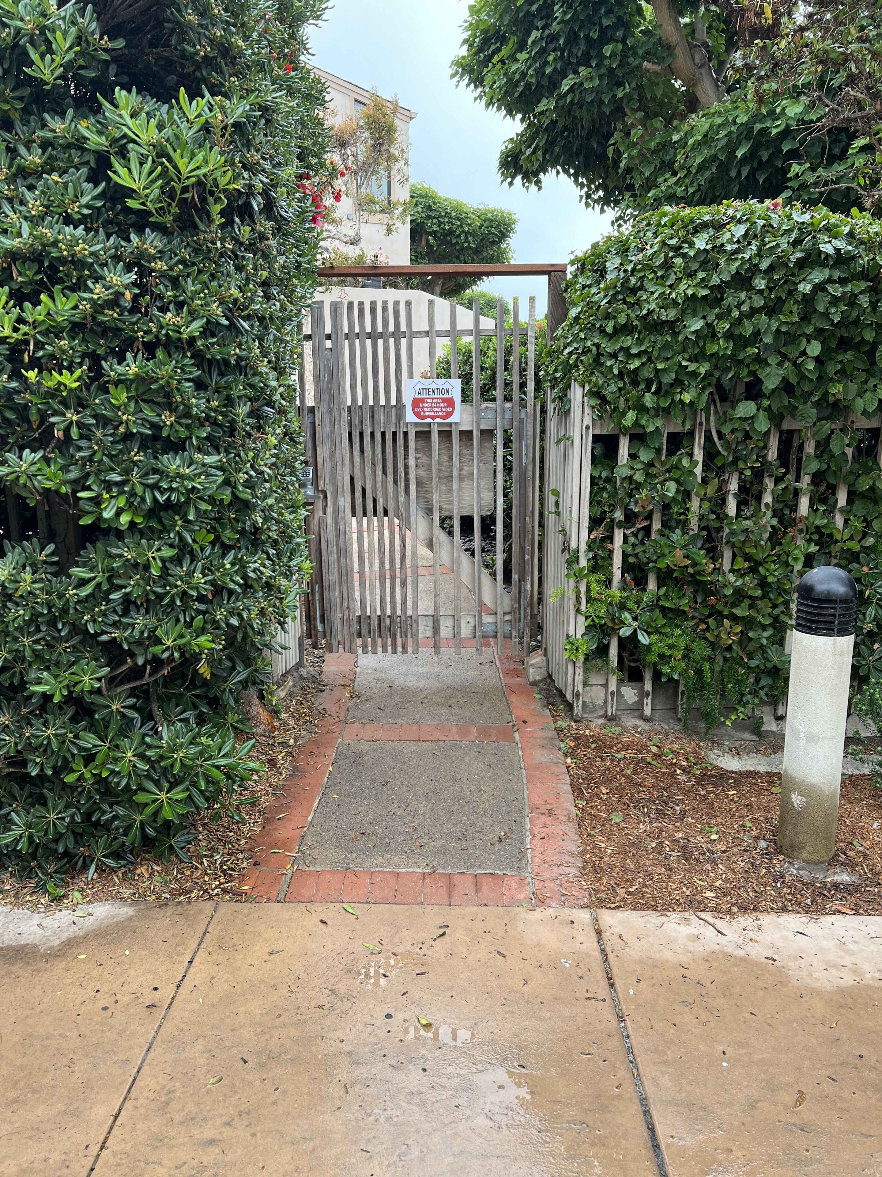 A gated entrance with a wooden fence and a sign.