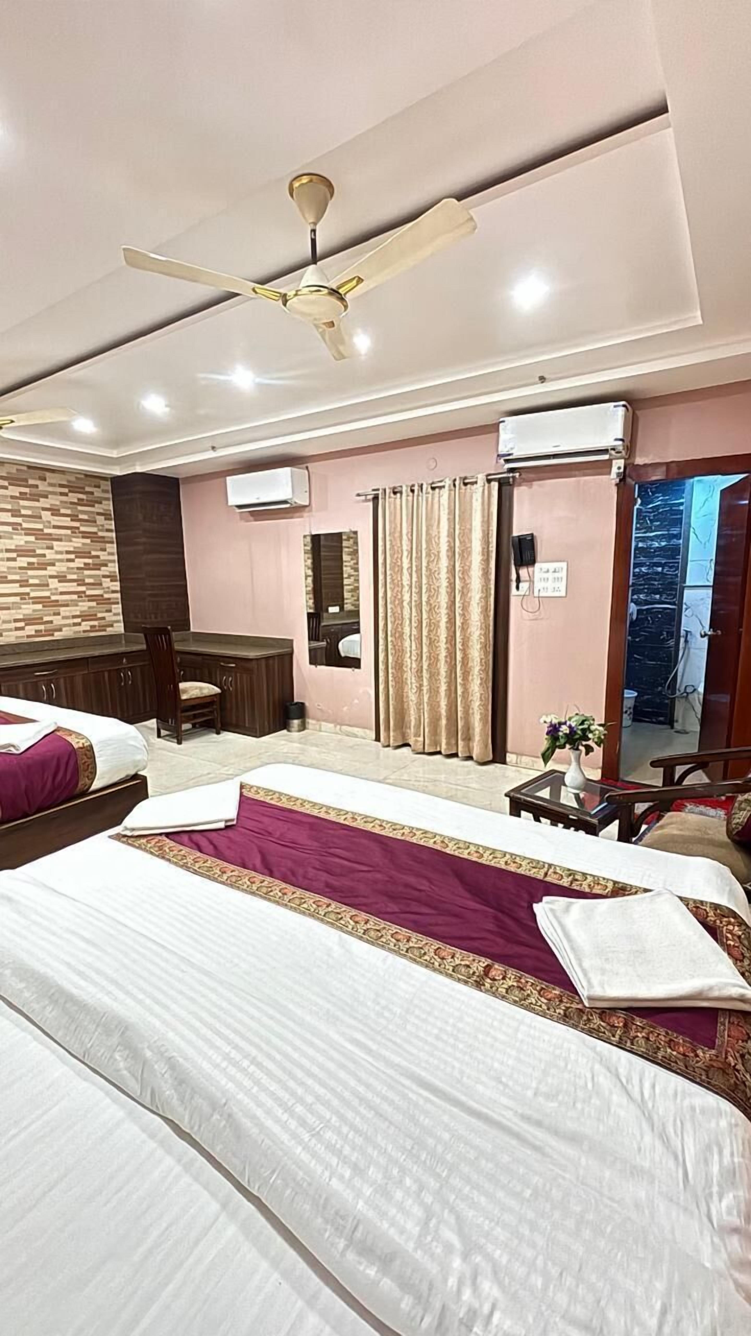 A hotel room with a bed, a desk, a chair, an air conditioning unit, and a ceiling fan.
