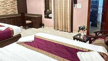 A hotel room with a bed, a desk, a chair, an air conditioning unit, and a ceiling fan.