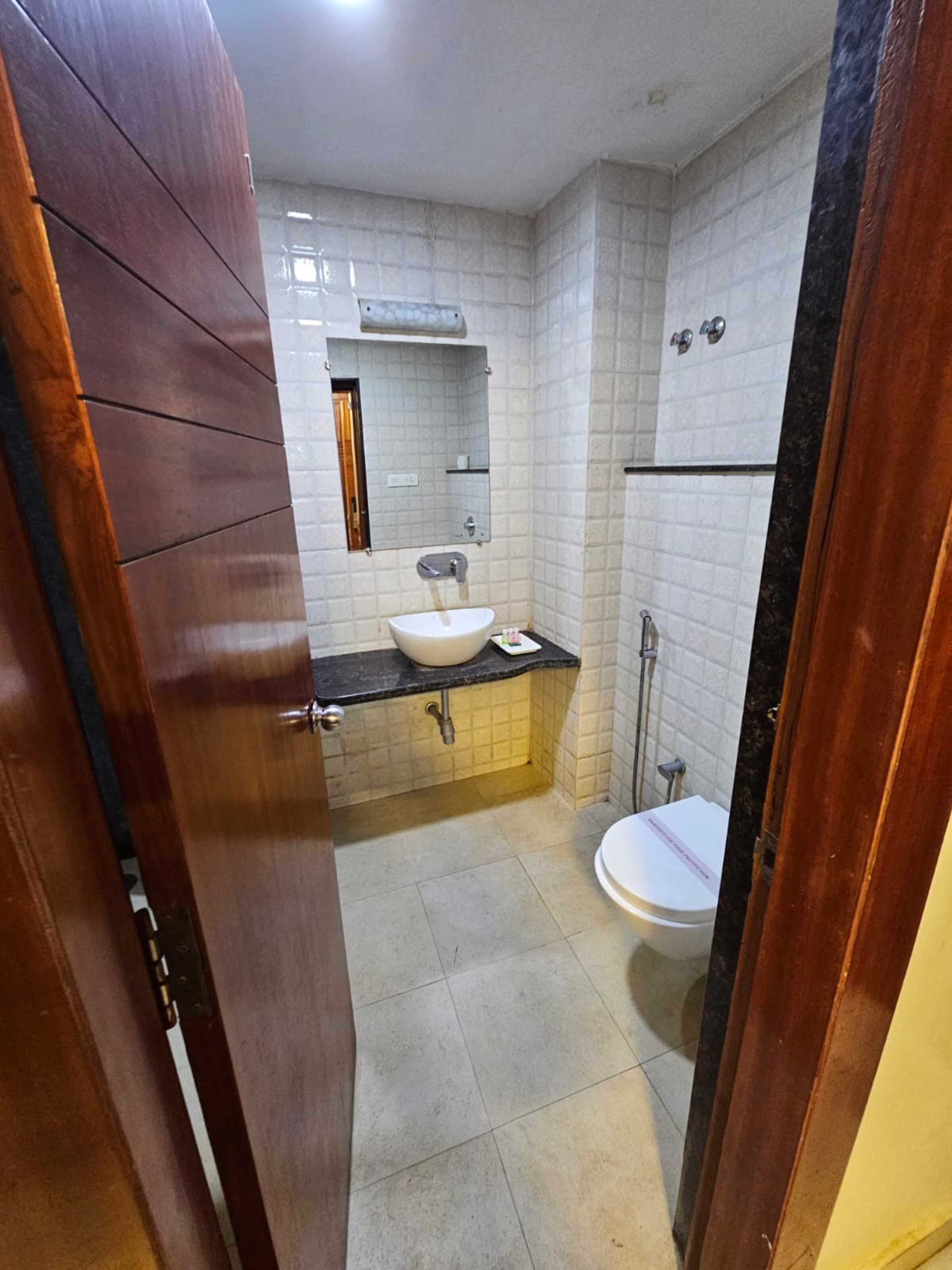 Un baño con lavamanos blanco, espejo e inodoro.