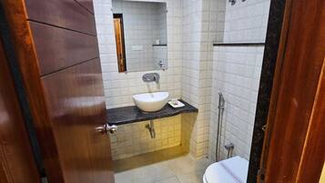 Un baño con lavamanos blanco, espejo e inodoro.