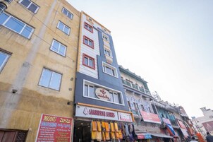 Un immeuble à plusieurs étages, avec différents commerces au rez-de-chaussée, dont une enseigne bien visible pour « Samriddhi Sarees ».