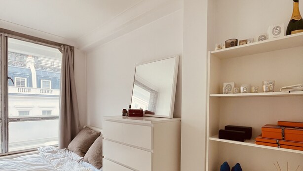 Une chambre à coucher comprenant un lit, une commode, un miroir et une étagère sur laquelle sont disposés divers objets.