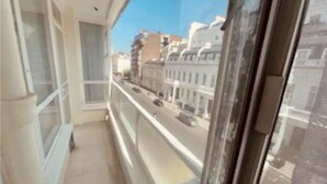 Un balcon étroit offrant une vue dégagée sur une rue et des immeubles.
