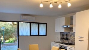 Una cocina moderna con armarios blancos, una estufa y un comedor con mesa y sillas.