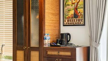 A hotel room with a wooden wardrobe, a bed, a bathroom with a sink, and a poster on the wall.