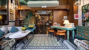 Un vestíbulo de hotel con una zona de estar central, una escalera y un comedor.