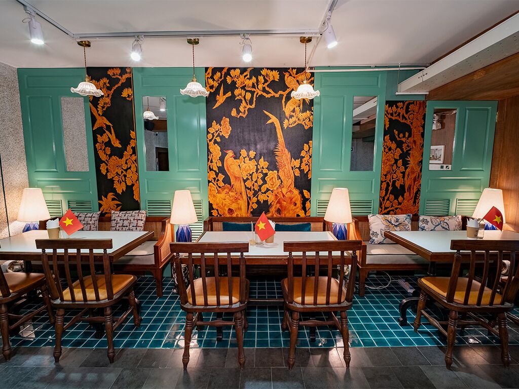 A restaurant with teal walls, wooden tables, and chairs.