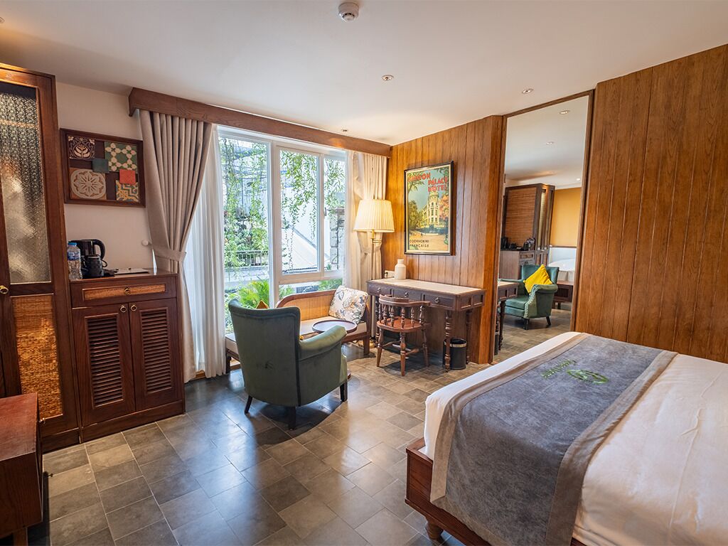 Une chambre d’hôtel avec un lit, un bureau, une chaise et une fenêtre avec des rideaux.