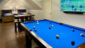 A pool table with balls, a television displaying a sports game, and a seating area with a table and chairs. - 4 Bedroom House with Game Room (Lexington)