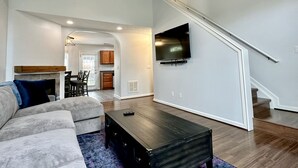 A modern living room with a sofa, coffee table, and a TV mounted on the wall. - 4 Bedroom House with Game Room (Lexington)