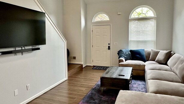 A living room with a flat-screen TV, a beige sofa, a coffee table, and a patterned rug. - 4 Bedroom House with Game Room (Lexington)