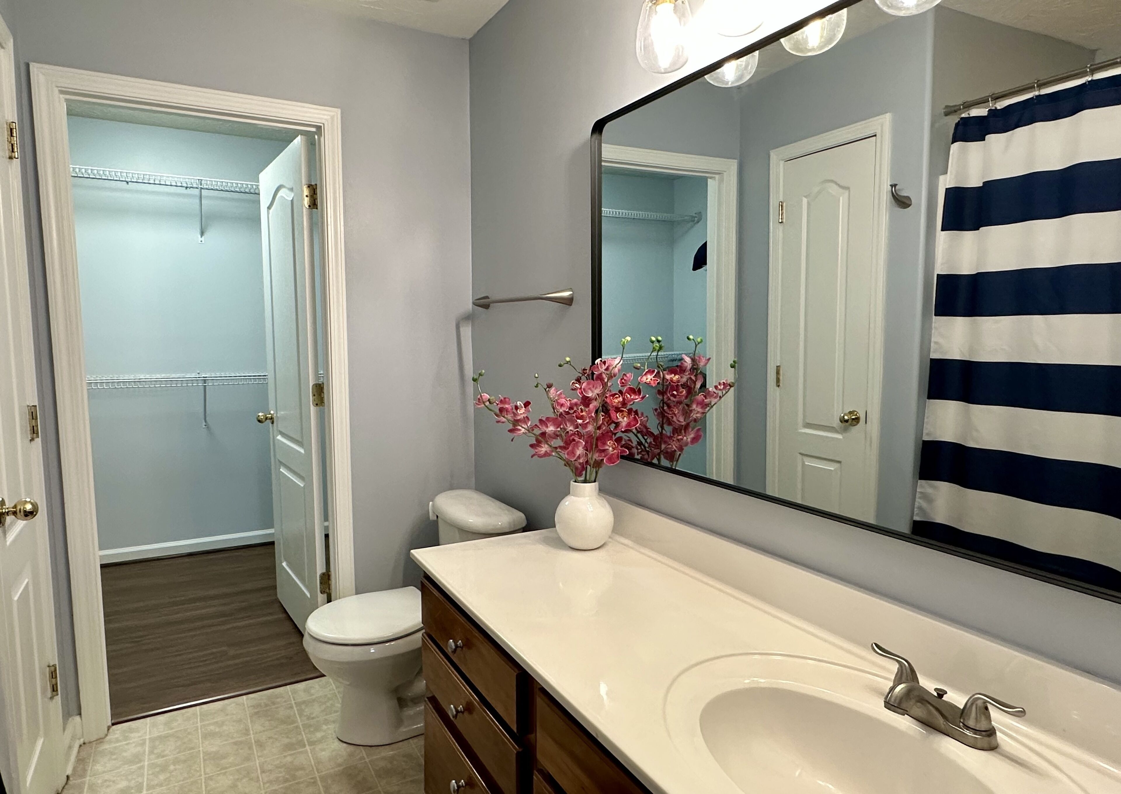 Une salle de bain avec un lavabo blanc, un miroir, des toilettes et un espace douche.