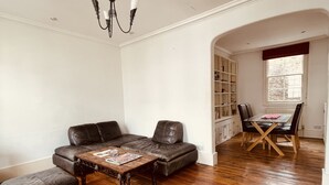 Un salon comprenant un canapé en cuir, une table basse en bois et un coin repas avec une table et des chaises en bois.