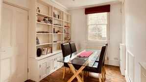 Un coin repas avec une table en verre, des chaises noires et une bibliothèque blanche.