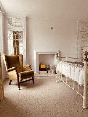 A room with a bed, a chair, a fireplace, and a window with curtains.