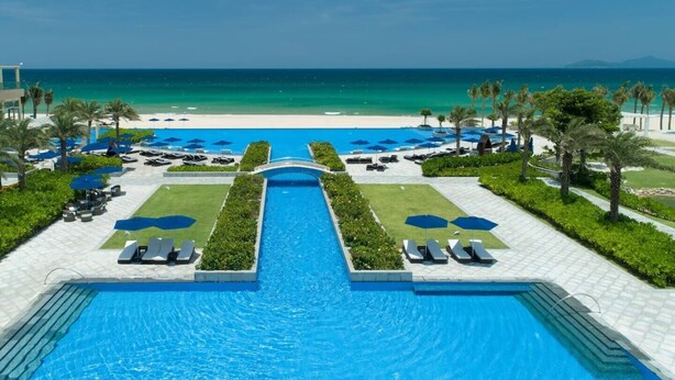 A resort pool with a clear view of the ocean, lounge chairs, and umbrellas. - Family-Friendly3BRVilla•BRGGolfView•PrivatePool•NearSea•FreePickup(5 Nights+) (Da Nang City)