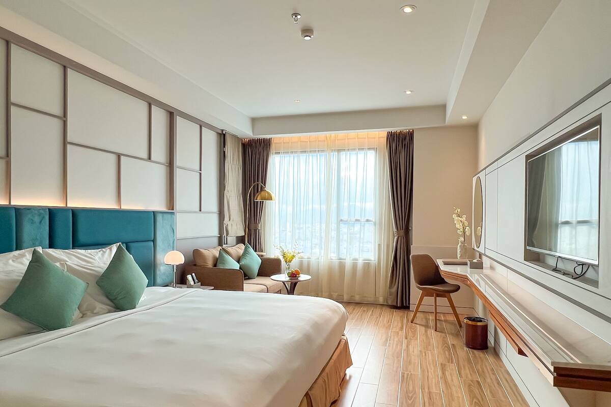 Una habitación de hotel moderna con una cama grande, un escritorio y una televisión.