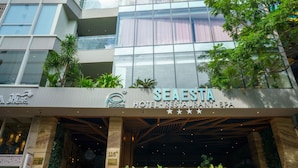 Un hotel moderno con fachada de vidrio, asientos exteriores y una escalera visible que conduce a la entrada.