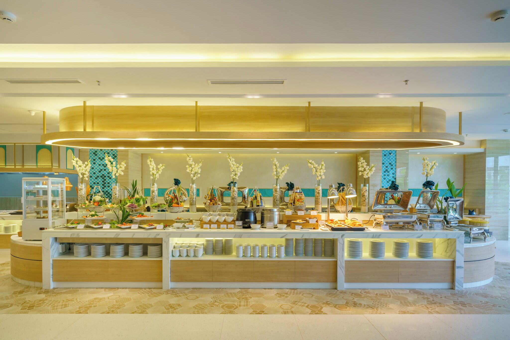 A buffet setup with various food items, a glass display case, and decorative plants.