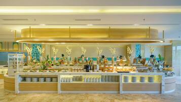 A buffet setup with various food items, a glass display case, and decorative plants.