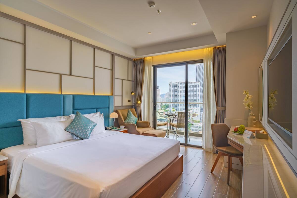Habitación de hotel con una cama grande, un escritorio, una silla y vistas a la ciudad.