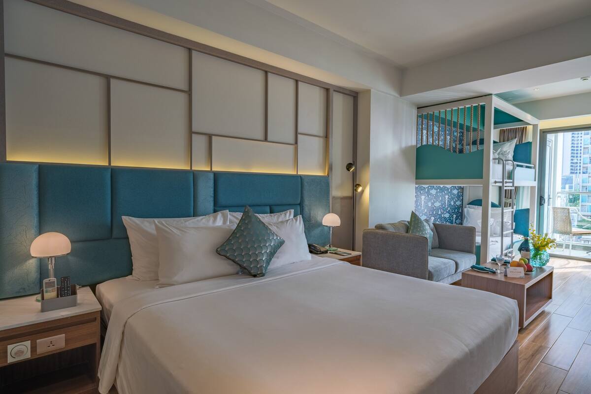Una habitación de hotel moderna con una cama grande, un espacio para sentarse y vistas a la ciudad.