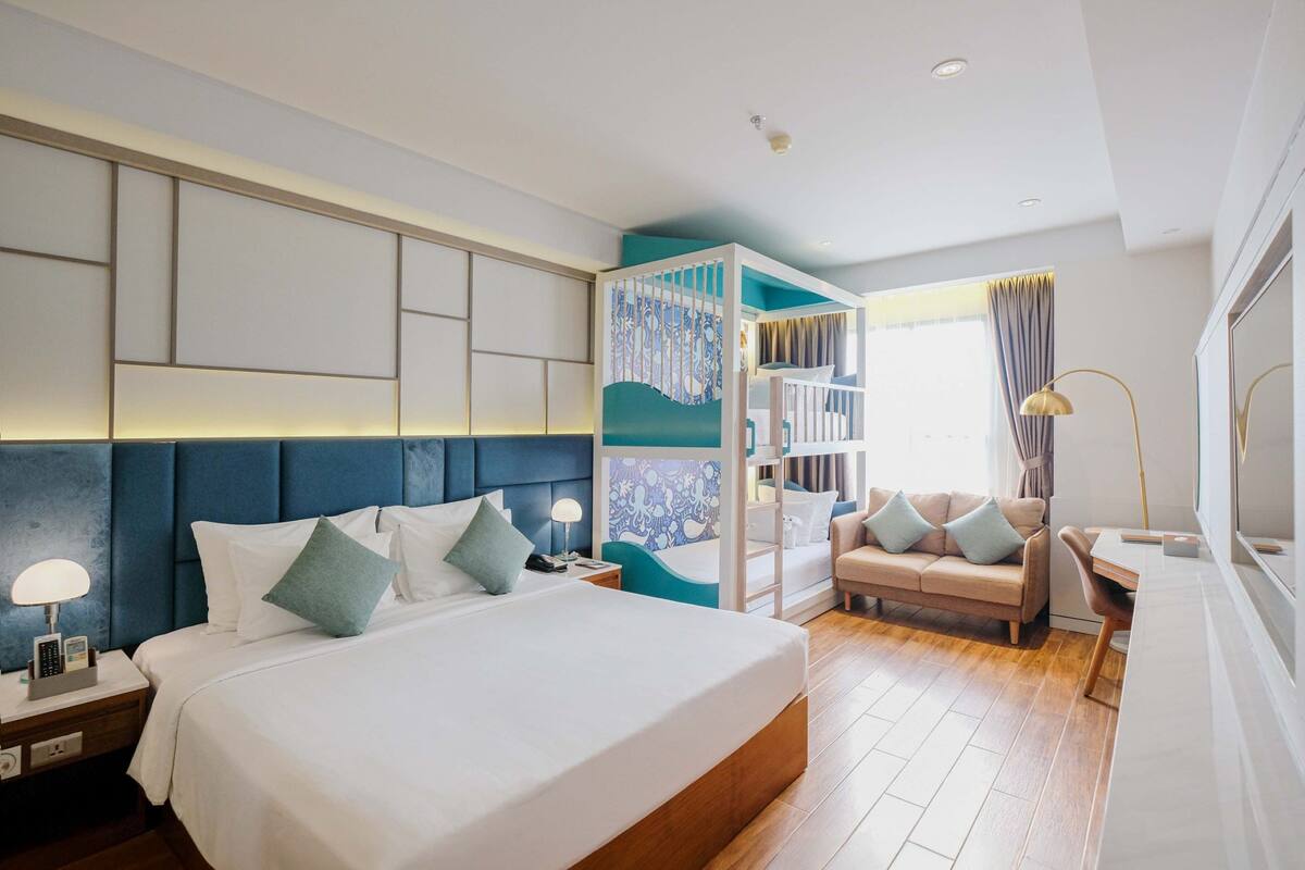 Una habitación de hotel moderna con una cama grande, un escritorio, una silla y una estantería.