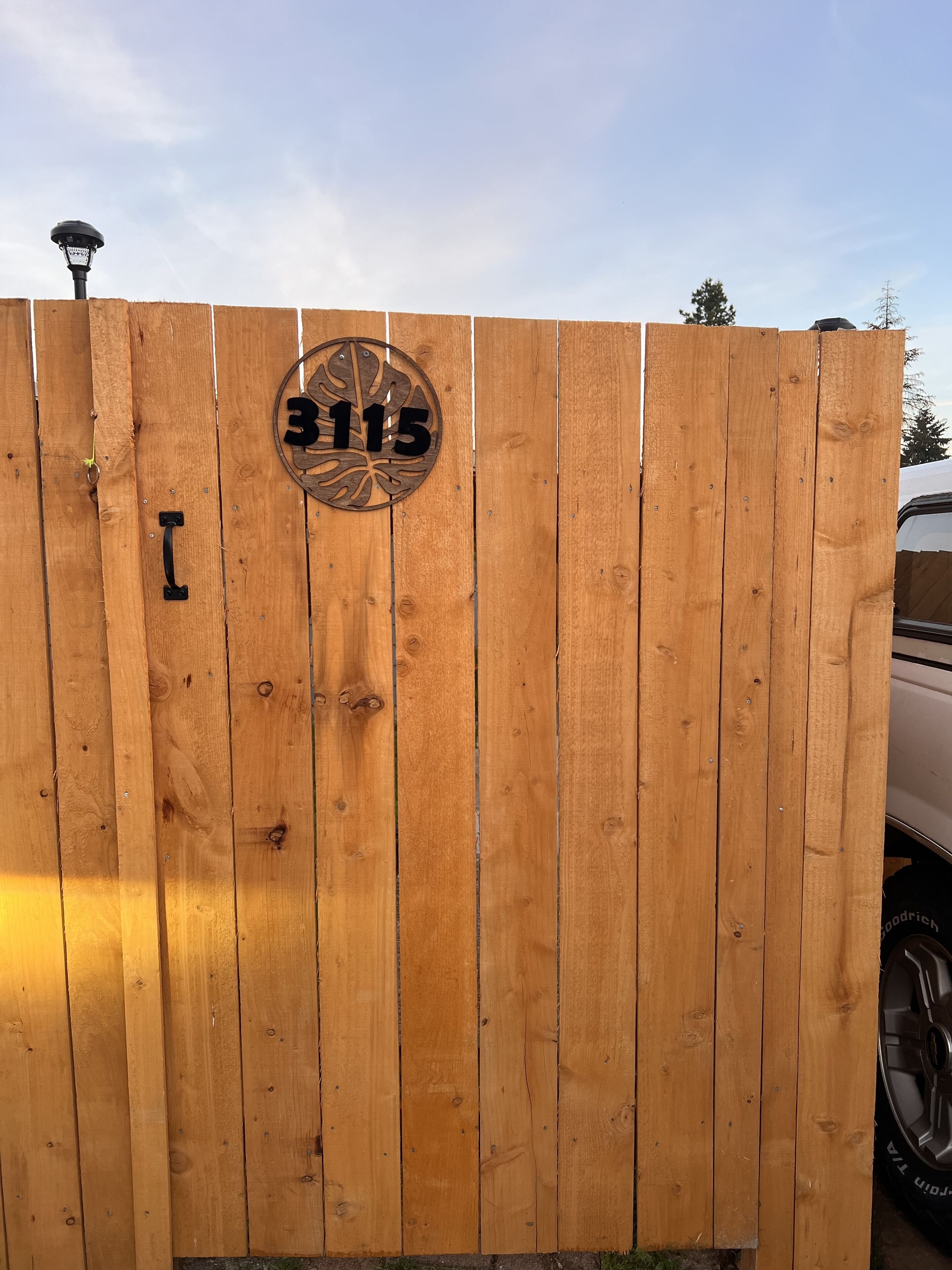 Une clôture en bois sur laquelle est fixé un panneau circulaire portant le numéro 3115.
